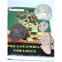 Four Pre-Columbian artefacts and a book, each of the heads modelled from clay, a black and a grey p.