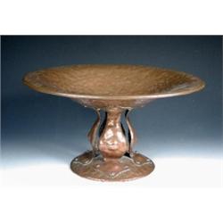 An Arts and Crafts copper tazza, the hammered bowl riveted to four organic straps ending in trefoil.