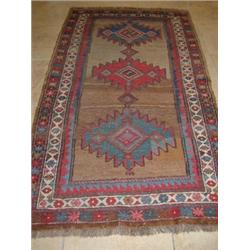 A Kazakh wool rug, the tan field enclosing three serrated medallions within rosette guard stripes a.