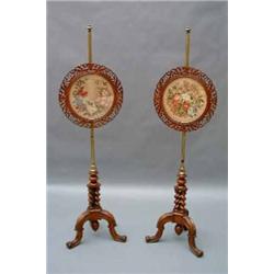 A pair of Victorian walnut pole screens, having circular fret-cut and pierced screens, inset with...