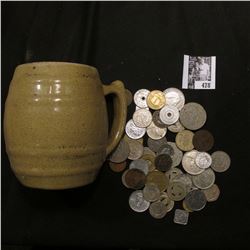 Stoneware Mug "Uhl Pottery Co. 16 Huntingburg Ind." with a large group of unsorted foreign coins and