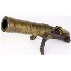 Antique small brass cannon with 8" turned barrel on iron mounts and screw type plunger, 13" overall.