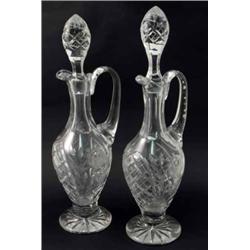 A pair of claret jugs, with stoppers, in the form of ewers with floral decoration and star cut ba...