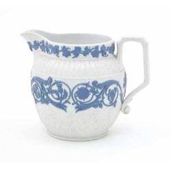 A Wedgwood milk jug, decorated with applied blue and moulded scrolling relief on matt white groun...