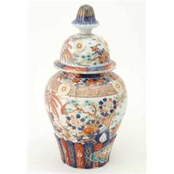 An Imari baluster vase and cover, decorated with trees, rocks and flowers within moulded borders....