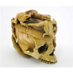 A Japanese ivory okimono, carved with a snake hunting toads upon a skull. 2.5ins...
