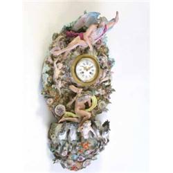 A large Meissen wall clock, circa 1860-80, the circular drum dial set into a tall shell and scrol...