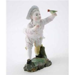A Hochst figure of a boy leaning forward with outstretched arm, holding a bird and wearing a pale...