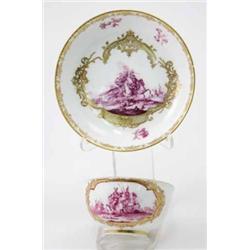 A Meissen cup & saucer decorated with panels of battle scenes in purple camaieu within elaborate...