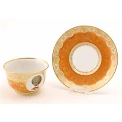 A Flight & Barr Worcester armorial teacup and saucer, enamelled with a peacock crest within round...