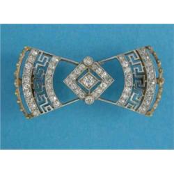 An Edwardian gold, diamond set bow brooch, with pierced Greek key decoration...