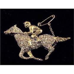 An 18ct gold brooch in the form of a jockey and rider, the horse pvé set with diamonds. See Illus...