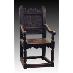An early 18th Century oak open armchair, with carved scroll toprail and panelled back with strapw...