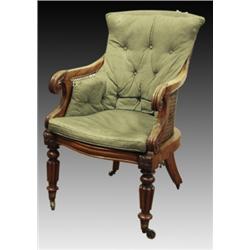 A George IV mahogany library armchair, circa 1830, the shaped cane back and seat with scroll leaf...
