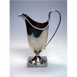 An Edwardian silver cream jug by the Haseler Bros, Chester 1904, of plain helmet shape raised from..