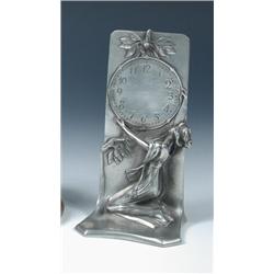An Art Nouveau pewter watch stand, possibly Belgian, a young lady in a long dress kneeling to hold..