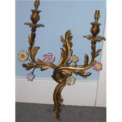 A pair of early 20th century gilt metal wall lights, each with two rococo foliate arms mounted with.