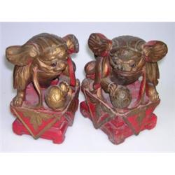 A pair of late 19th century Chinese carved and painted Buddhist lions each of the gilded animals se.