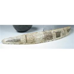 A scrimshaw baleen rib bone line engraved with masks and beasts, stylised inscriptions surrounding..