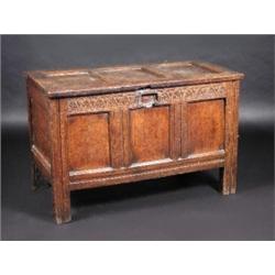 A 17th century oak coffer, the three panel rectangular rising top above a carved frieze and three p.