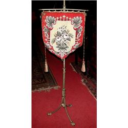 A 19th century fire screen, the bead worked shield shaped panel supported on an adjustable brass co.