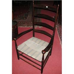 A stained beech Shaker chair, the finial headed ladder back above bowed arms and slung seat, standi.