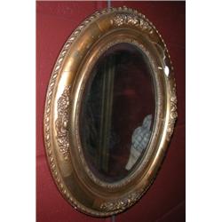 A pair of 19th century gilt framed mirrors, each with oval bevelled plate within a carved moulded f.