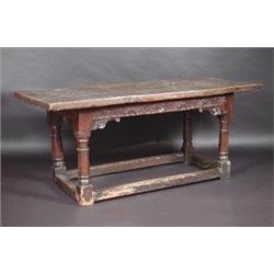 A 17th century oak refectory table, the rectangular top above a carved frieze with scrolling bracke.