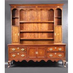 An 18th century oak dresser, the closed upper section with moulded cornice above a Prince of Wales..