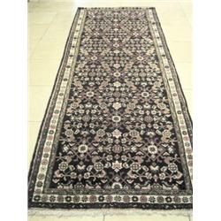 A Caucasian wool runner, the midnight blue field enclosing a repeating Herati pattern within a rose.