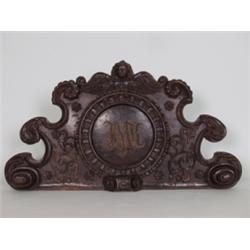 Relief. Lindenholz geschnitzt und gebeizt. Runde, gerahmte Monogrammkartusche, bekrönt von geflüg...