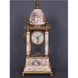 Pendule. Porzellan und vergoldete Bronze. Zwischen vier Säulen hängendes, fassartiges Uhrgehäuse...
