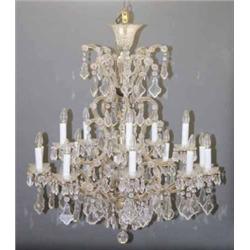 A sixteen light chandelier, with fifteen scroll branches set flattened crystal drops and cut icic...