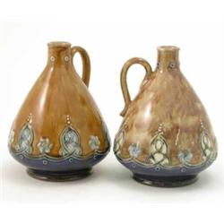 A pair of Royal Doulton glazed stoneware ewers, with stylised floral devices against a mottled br...