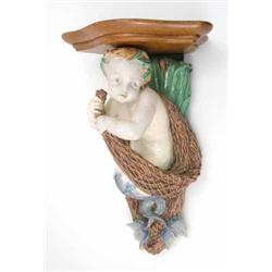 A Minton majolica wall bracket, with shaped oak shelf, the support in the form of a merboy clutch...