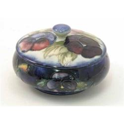 A Moorcroft Pansy powder bowl, and cover, circa 1935, leafy petal design against a deep blue grou...