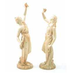 A pair of Victorian Royal Worcester statuettes, Captivity and Liberty, each holding a bird aloft,...