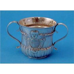 A George II silver porringer, with reeded twin scroll handles and decorated with an angel mask ca...