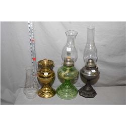 Three vintage oil lanterns including green glass with chimney, cast lamp with chimney and brass colo