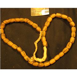 20" Strand of Old Indian Trade Beads, sand cast, strung on braided straw.