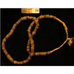 20" Strand of Old Indian Trade Beads, sand cast, strung on braided straw.