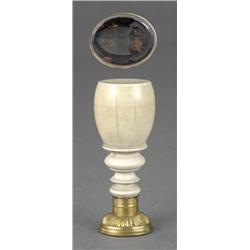 A large turned ivory desk seal, of maul form, with reeded and lobed gilt-metal mount, the oval ma...