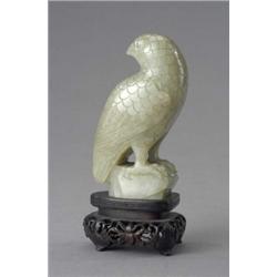 A Chinese jade carving of a parrot, perched on a rock, its head turned, with boldly defined pluma...