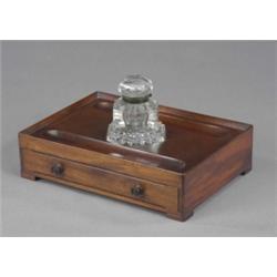 An early Victorian mahogany rectangular inkstand, the glass hexagonal well with hinged cover, the...