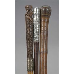 Three Eastern walking sticks, one with silver coloured metal handle chased with village and palms...