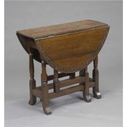 An oak oval gateleg table, carved with a strapwork band, the turned underframe with out-turned fe...