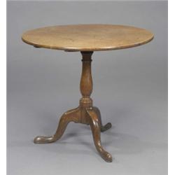 A George III oak tea table, the circular top tilting on a baluster pillar and cabriole tripod bas...