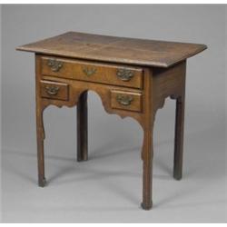 A George III oak lowboy, the moulded oversailing top above one long and two short ovolo moulded d...