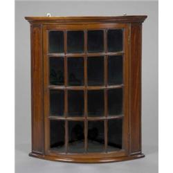 A mahogany hanging corner cupboard, of deep bow form, enclosed by an astragal moulded door glazed...