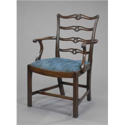 A mahogany elbow chair, in George II style, the pierced serpentine ladder back carved with leaf s...